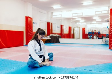 Young Woman Stretching In A Dojo Wearing Taekwondo Dobok