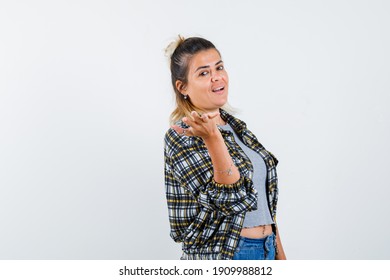  Young Woman Stretching Hands Toward Camera, Looking Over Shoulder In Checked Shirt, Grey T-shirt And Jean Shorts And Looking Serious , Front View. 