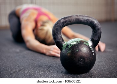 Young woman stretching her back after a heavy kettlebell workout in a gym - Powered by Shutterstock