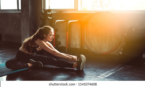 Young Woman Stretching Her Right Leg In Gym.Sporty Woman Stretching At Gym.