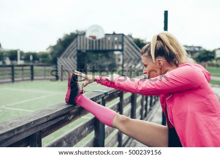 Young woman stretching legs before training outdoors