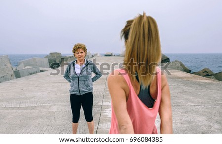 Two women walking by sea pier