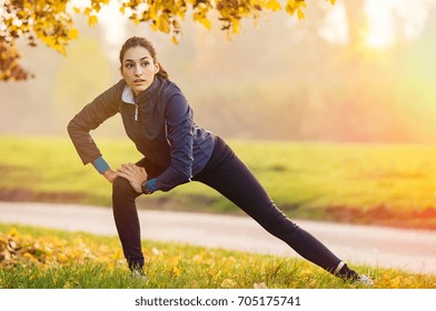 Young Woman Stretching And Warming Up At Park During Sunset. Attractive Girl Stretching Before Fitness In The Autumn Park. Beautiful Sporty Girl Doing Fitness Outdoor During Winter.