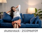 Young woman is stretching while sitting on her comfortable sofa, enjoying her free time at home