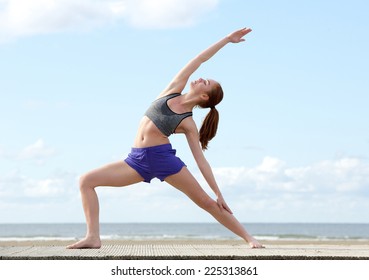 Young woman stretching in yoga position at the beach