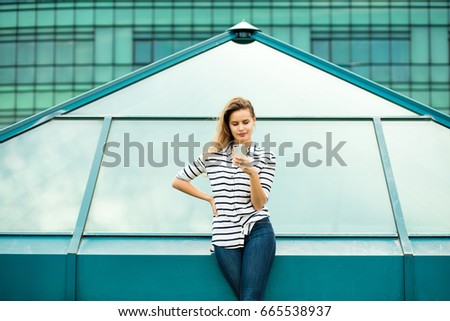 young woman in stripes standing on a glass construction, in an urban area