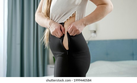 Young woman struggling to xip up tight dress. Concept of excessive weight, obese female, dieting and overweight problems.