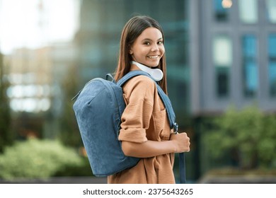 Young woman student with backpack walking through campus. Joyful pretty lady posing at university park, exuding positivity and a thirst for knowledge amidst an atmosphere of academic pursuit - Powered by Shutterstock