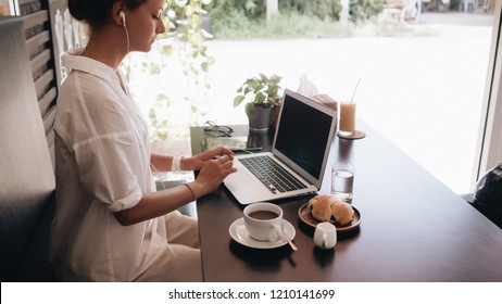 Young woman student with laptop sitting in cafe and working with laptop - Shutterstock ID 1210141699