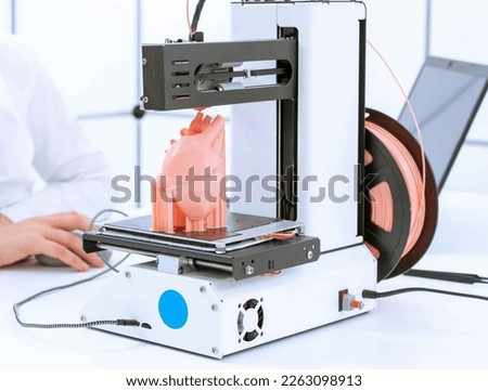 young woman student prints a model of the anatomical human heart on a 3D printer