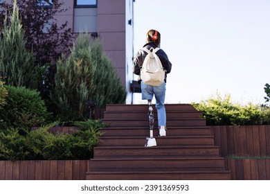 Young woman student with prosthetic leg walking upstairs in city. Disabled woman with prosthetic leg using stairs. Woman with leg prosthesis equipment. - Powered by Shutterstock