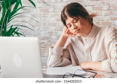 Young Woman Student Sitting At Desk Full With Books Textbooks Looking At Computer Screen To Unfinished Homework Feels Tired Bored And Unmotivated, Girl Loaded With Tasks, Work Backlog Overflow Concept