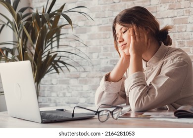 Young Woman Student Sitting At Desk Full With Books Textbooks Looking At Computer Screen To Unfinished Homework Feels Tired Bored And Unmotivated, Girl Loaded With Tasks, Work Backlog Overflow Concept