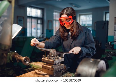 Young Woman Student Works On An Automatic Lathe CNC, Industrial Workshop. Concept Vocational Education Turner.