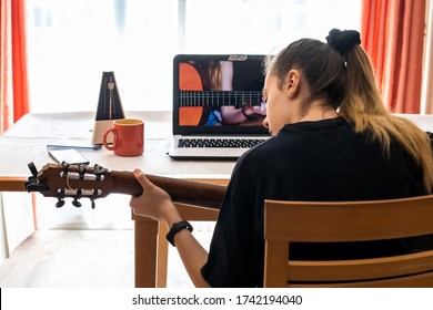 Young Woman Studying Guitar Lessons At Home