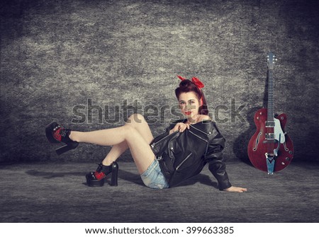 A young woman in the style of pin-up with a guitar sitting in abandoned interior.