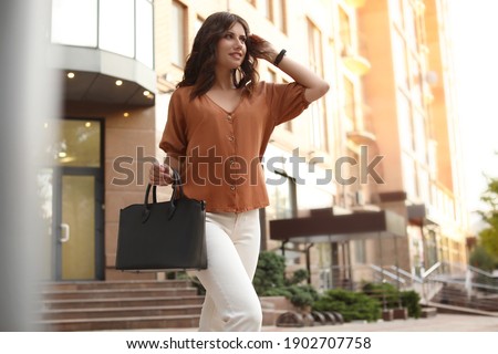 Young woman with stylish black bag on city street