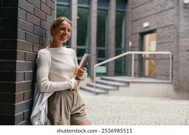 A young woman, stylish and relaxed, is seen in a modern urban environment, using her notebook - Powered by Shutterstock