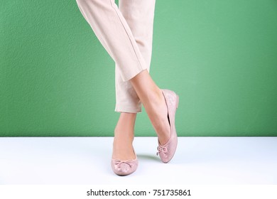Young woman in stylish shoes against color wall