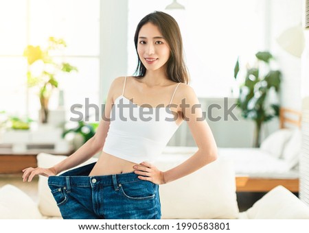 young woman succeeded in losing weight. She wore large size jeans  long time ago, showed her figure very confidently