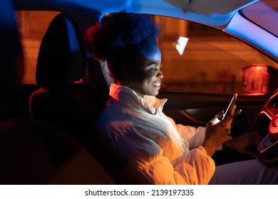 Young Woman Suffer From Smartphone Addiction, Spend Day And Night In Social Media. African Girl Sit In Dark Car Holding Mobile Phone In Hand, Texting, Scrolling Websites And Communicating Via Internet