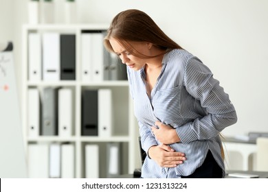 Young Woman Suffering From Abdominal Pain In Office