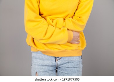 Young woman suffering from abdominal pain. Gray background. - Shutterstock ID 1971979505
