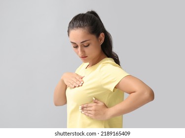 Young Woman Suffering From Breast Pain On Grey Background