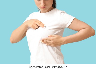 Young Woman Suffering From Breast Pain On Blue Background, Closeup