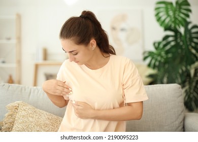 Young woman suffering from breast pain at home
