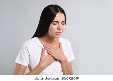Young woman suffering from breathing problem on light background - Shutterstock ID 2063929049