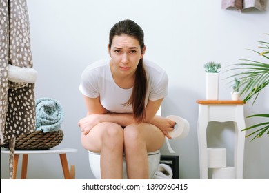 Young Woman Suffering From Constipation On Toilet Bowl At Home