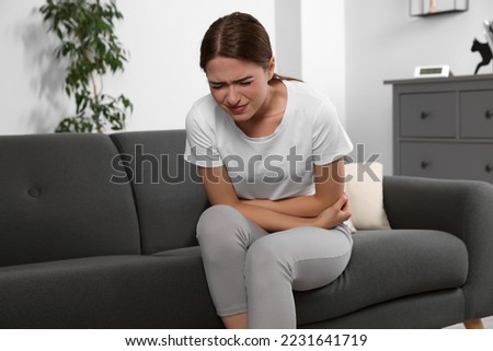 Young woman suffering from cystitis on sofa at home Сток-фото © 