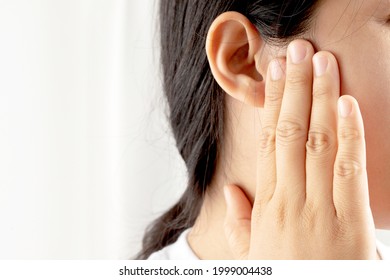 Young woman suffering from earache and tinnitus Causes of ear pain include otitis media and earwax buildup.