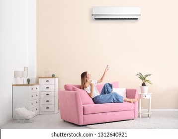 Young Woman Suffering From Heat Near Broken Air Conditioner At Home