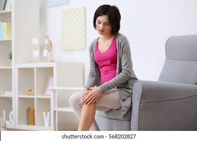 Young Woman Suffering From Pain In Knee At Home