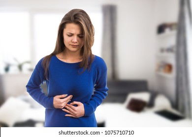 Young Woman Suffering Stomach Ache Pressing Abdomen Because Of Burn Acid As Digestive Illness Problem Concept On Indoor Room Background