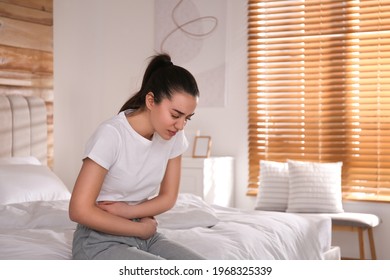 Young woman suffering from stomach ache on bed at home. Food poisoning