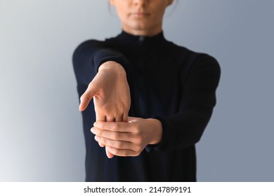 Young woman suffering from wrist pain, provide basic stretch excercise against pain. Holding right hand out in front. Stretching forearm before exercising.  - Shutterstock ID 2147899191