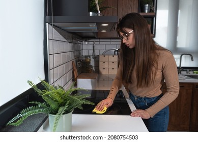 Young Woman Suffers From Depression After A Breakup Or Divorce And From Obsessive Compulsive Disorder OCD Cleans Kitchen Cook Top To Calm Her Nerves. Serious Stressed Female Rubbing The Home