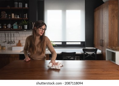 Young Woman Suffers From Depression After A Breakup Or Divorce And From Obsessive Compulsive Disorder OCD Cleans Kitchen Cook Top To Calm Her Nerves. Serious Stressed Female Rubbing The Home