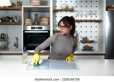 Young Woman Suffers From Depression After A Breakup Or Divorce And From Obsessive Compulsive Disorder OCD Cleans Kitchen Cook Top To Calm Her Nerves. Serious Stressed Female Rubbing The Home