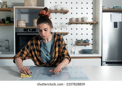 Young Woman Suffers From Depression After A Breakup Or Divorce And From Obsessive Compulsive Disorder OCD Cleans Kitchen Cook Top To Calm Her Nerves. Serious Stressed Female Rubbing The Home