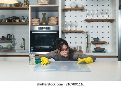 Young Woman Suffers From Depression After A Breakup Or Divorce And From Obsessive Compulsive Disorder OCD Cleans Kitchen Cook Top To Calm Her Nerves. Serious Stressed Female Rubbing The Home