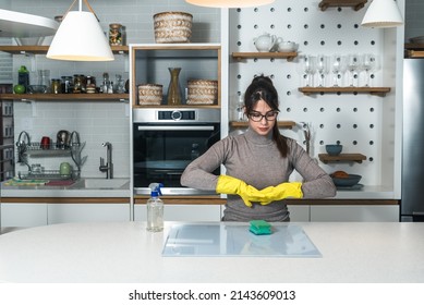 Young Woman Suffers From Depression After A Breakup Or Divorce And From Obsessive Compulsive Disorder OCD Cleans Kitchen Cook Top To Calm Her Nerves. Serious Stressed Female Rubbing The Home