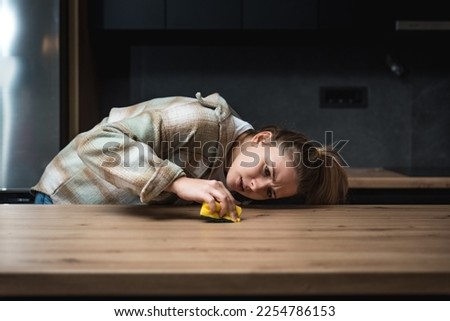 Young woman suffers from depression after a breakup or divorce and from obsessive compulsive disorder OCD cleans kitchen cook top to calm her nerves. Serious stressed female rubbing the home