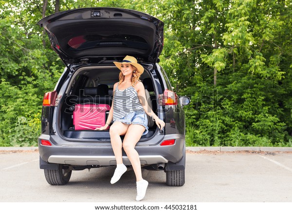 Young woman and suitcase.\
Vacation concept. Car trip. Summer travel. Girl traveling with\
suitcases