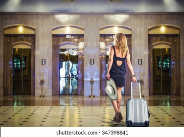 Young Woman with suitcase walking at the hotel lobby
