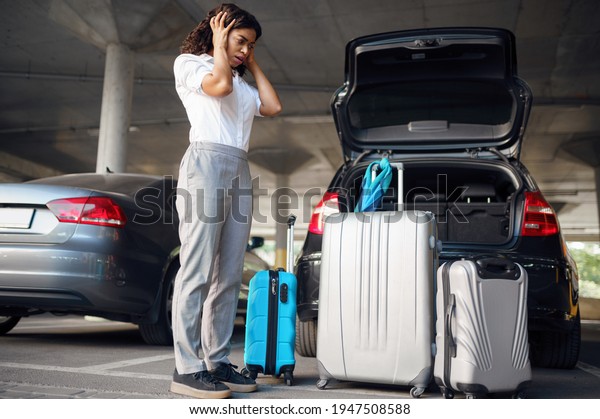 Young woman\
with suitcases in a panic, car\
parking