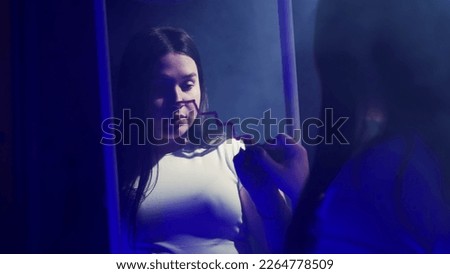 Young woman summoning the Queen of Spades while painting a staircase with lipstick on a mirror
